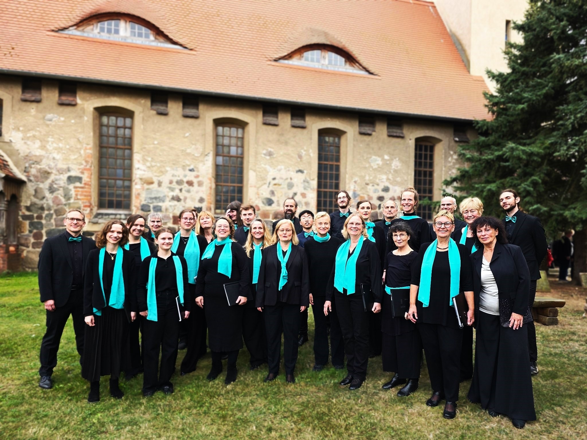 Gruppenfoto des Chores Canto Ergo Sum in schwarzer Kleidung mit türkisen Schals